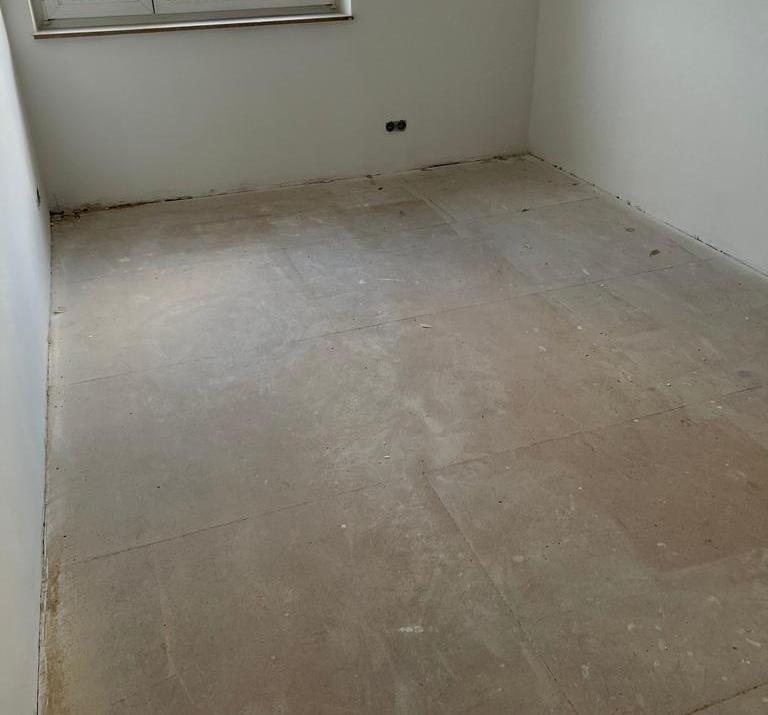 Zimmer mit freigelegtem Rohboden vor der Fußbodenheizung