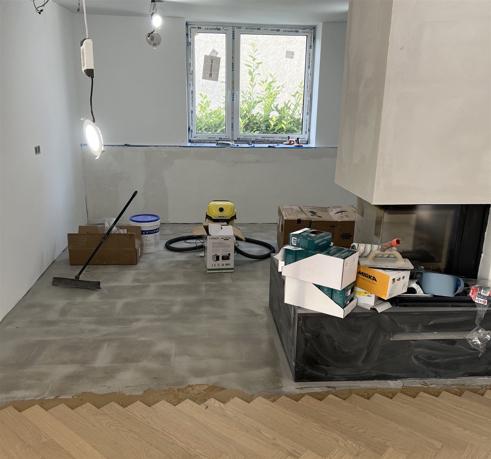 Zimmer mit Kamin und Estrich vor dem Verlegen des Fischgrät-Parketts