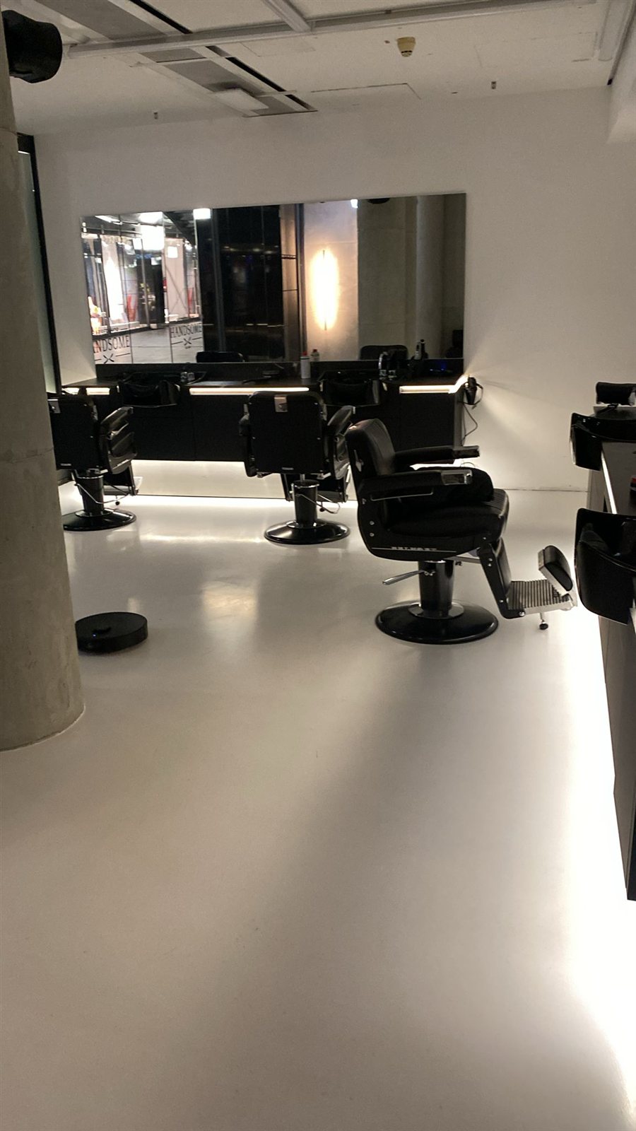 Barbershop-Stühle vor beleuchtetem Spiegel im umgebauten Salon