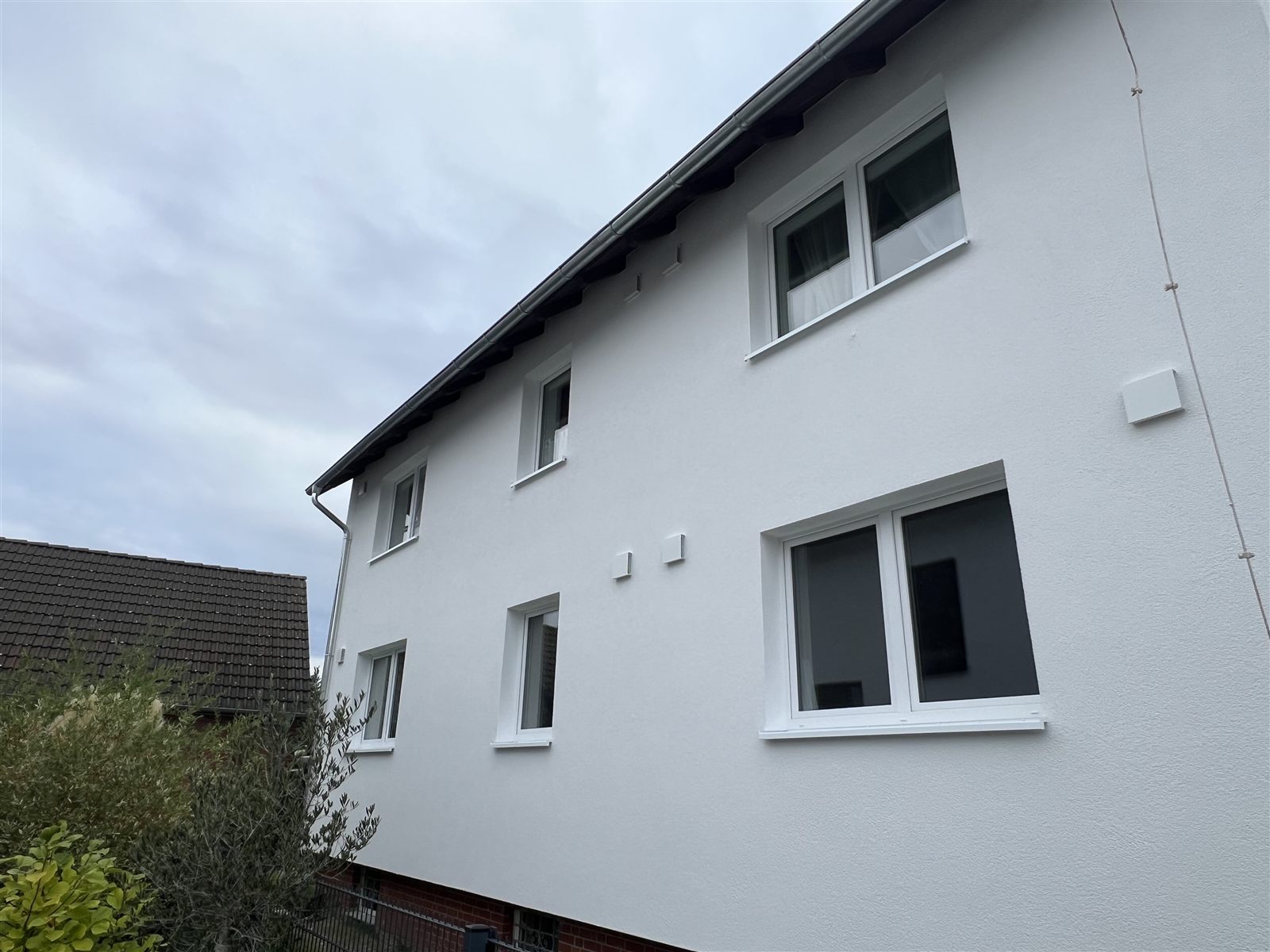 Längsseite des Hauses in Garbsen nach der Sanierung mit gedämmter, weiß verputzter Fassade