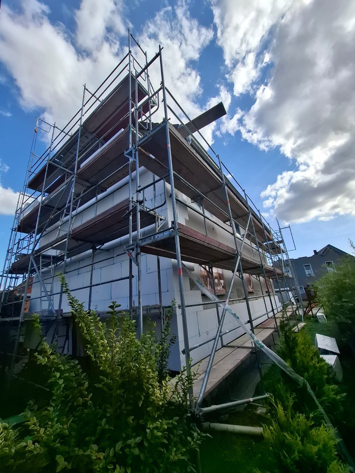 Fassade vollständig mit weißen Dämmplatten belegt, bereit für Armierung und Putz