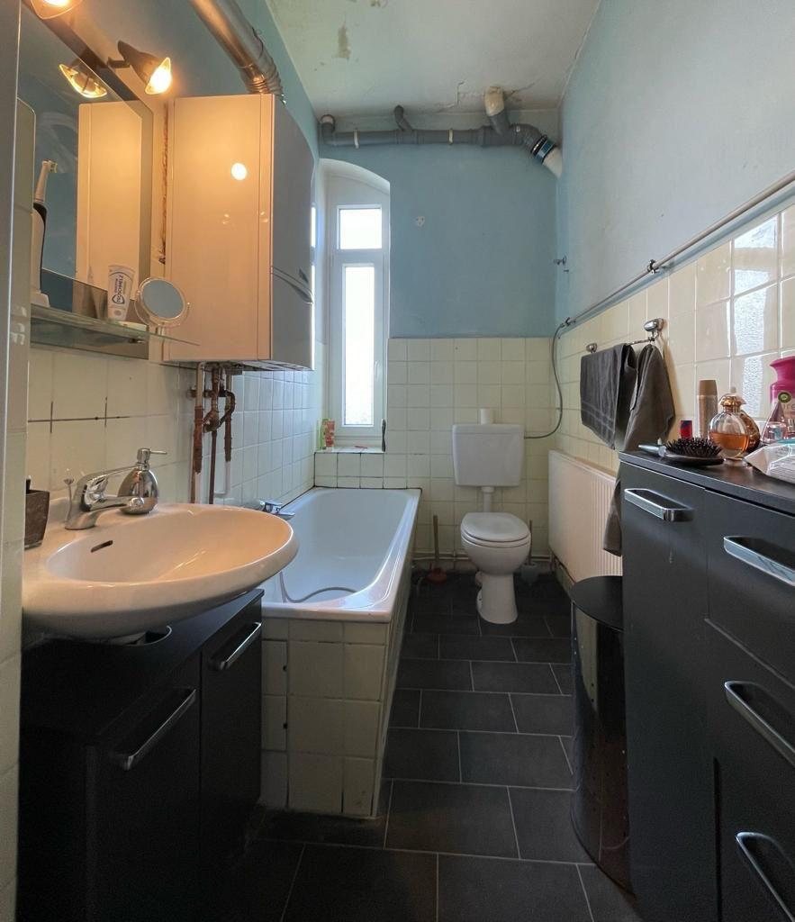 Altes Badezimmer vor der Sanierung mit gelben Fliesen und Eckbadewanne