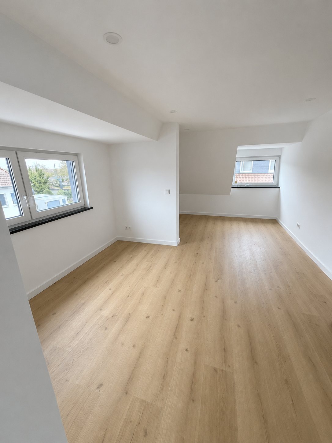 Ausgebautes Dachgeschoss in Hannover mit Vinylboden, weißen Wänden und Dachschrägen