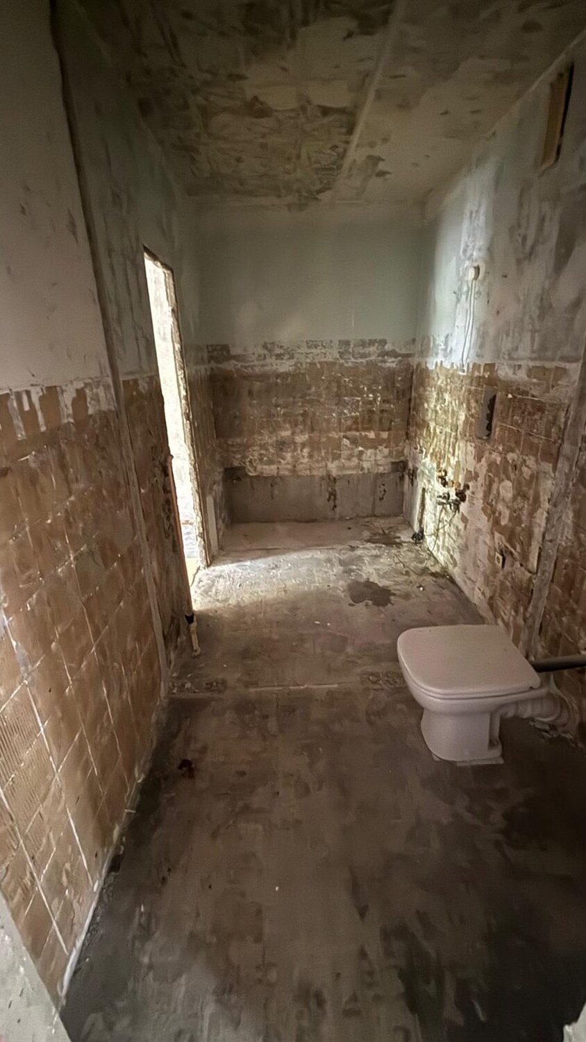 Dasselbe Badezimmer nach dem Rückbau: Fliesen abgeschlagen, Sanitärobjekte demontiert