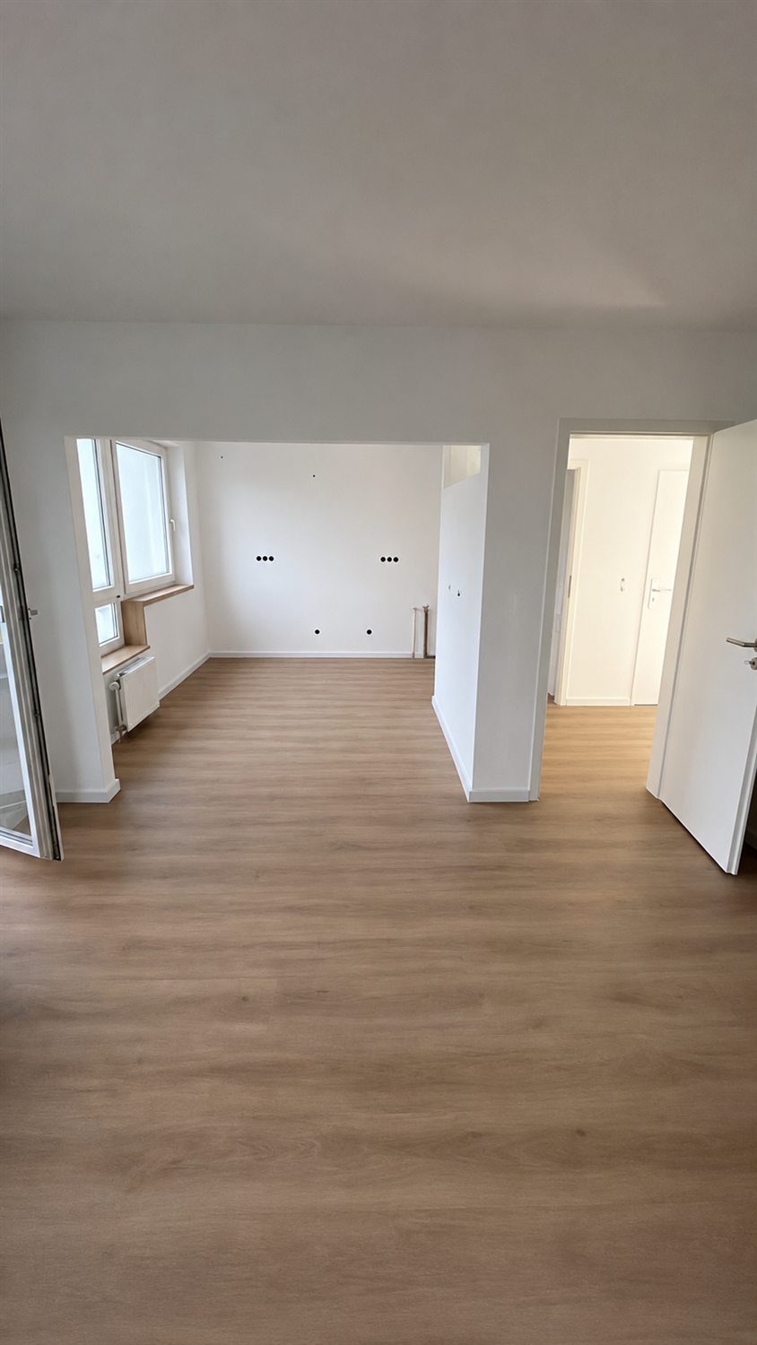 Wohnzimmer nach der Wohnungssanierung mit Wanddurchbruch und durchgehendem Vinylboden