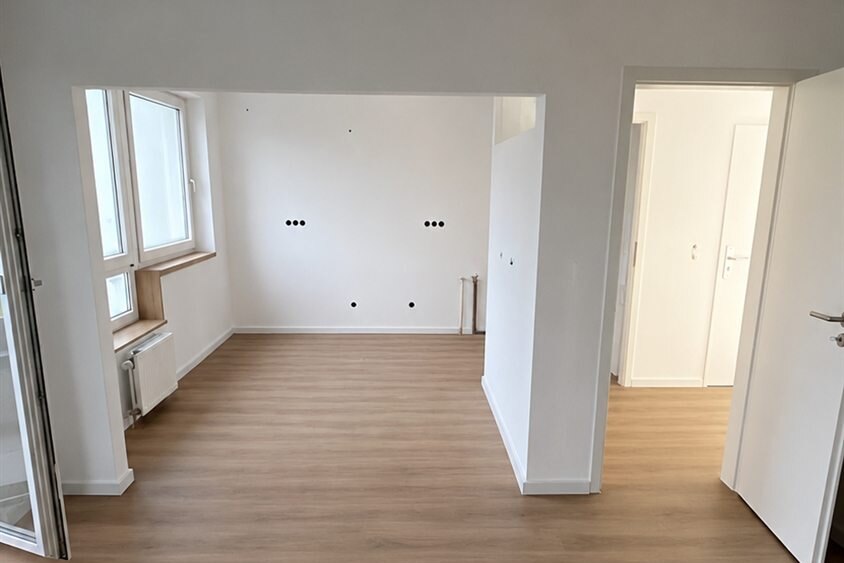 Wohnzimmer nach der Wohnungssanierung mit Wanddurchbruch und durchgehendem Vinylboden
